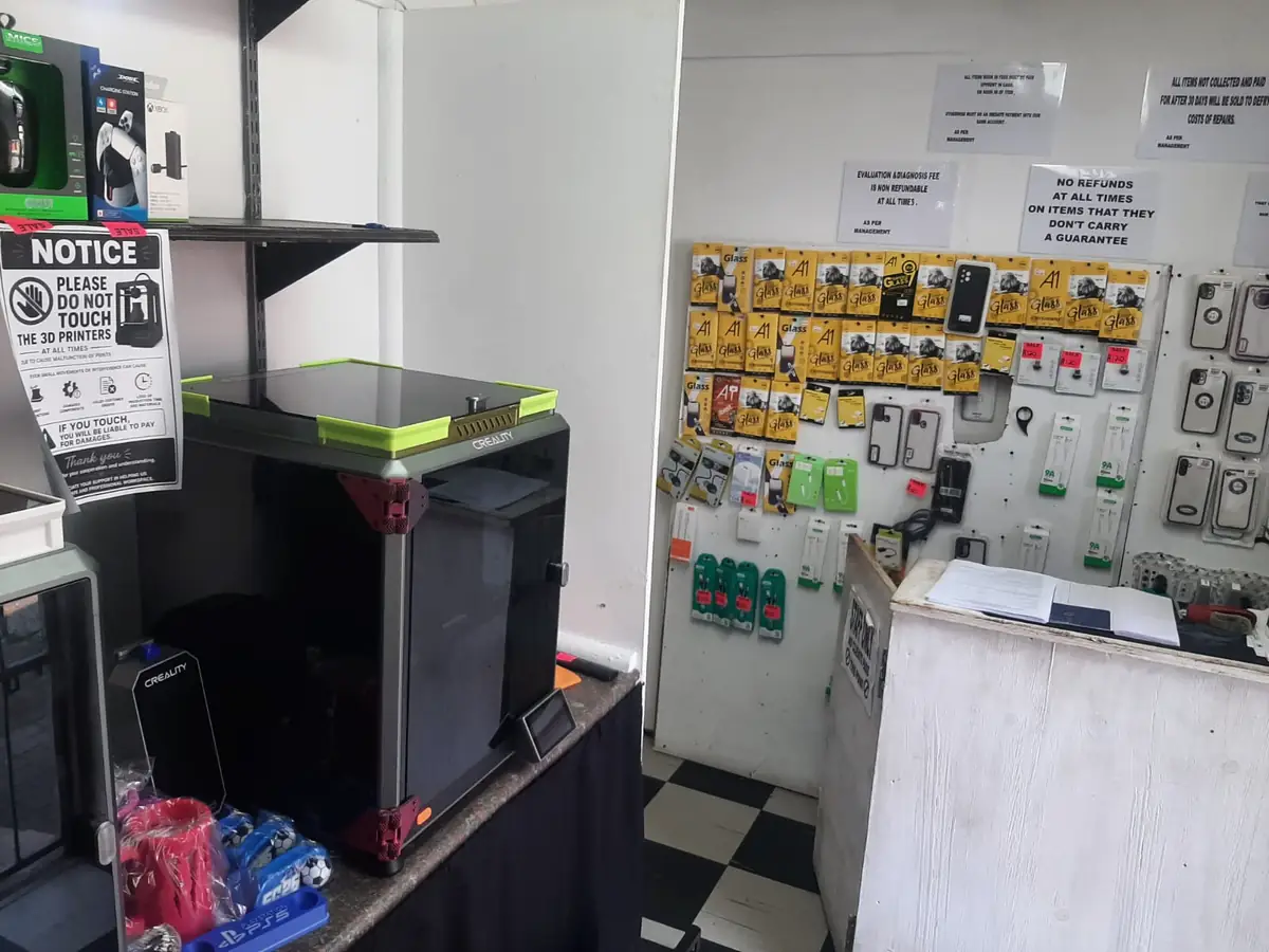 Inside Static PC Repairs: the counter, a wall of screen protectors, phone covers and cables, and two 3D printers