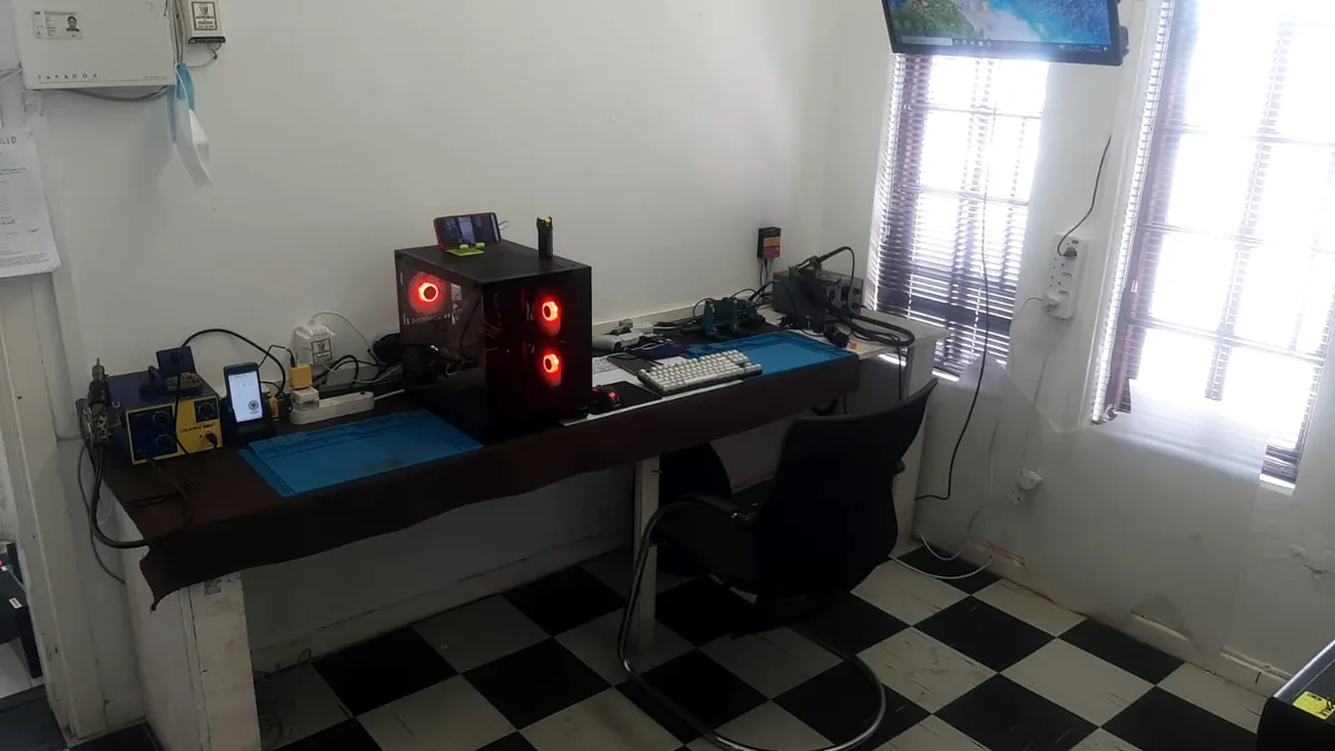 The Static PC Repairs workshop: a repair bench with soldering and hot air stations, blue silicone repair mats and a desktop PC with red fans